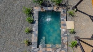 Aerial view of a swimming pool surrounded by trees and stone patio in Dominical.