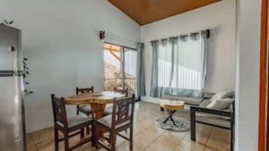 Bright living room with large windows, sofa, and dining area in Dominical.