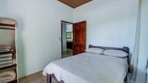 Comfortable bedroom with a large bed and wooden door in Dominical.
