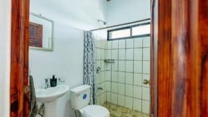 Bathroom with shower, sink, and toilet in a tropical home in Dominical.