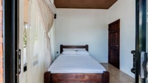 Simple bedroom with wooden bed frame and white bedding in Dominical.