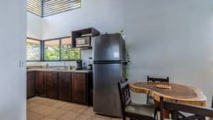 Modern kitchen with refrigerator, microwave, and dining table in Dominical.