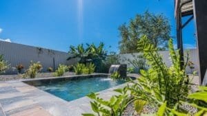 Outdoor pool with lush garden and clear blue sky in Dominical.