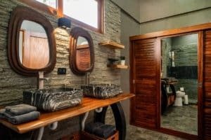 Modern bathroom with stone sinks, wooden accents, and a separate shower area in Uvita.