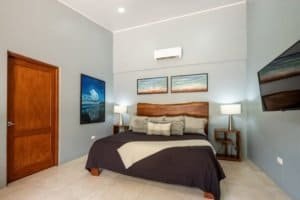 Modern bedroom with ocean-themed art and cozy bedding in Uvita, Costa Rica.