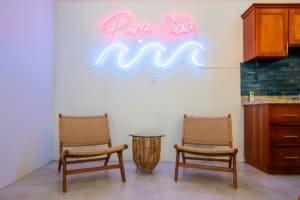 Modern interior with neon sign 'Pura Vida' and two chairs in Uvita.