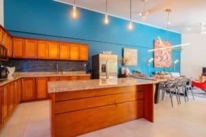Stylish kitchen with wooden cabinets and blue accent wall in Uvita.