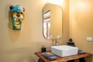Modern bathroom with a colorful tiger mask wall art and a white sink.