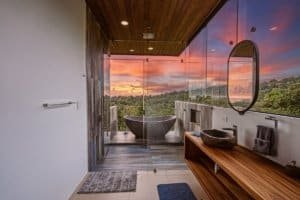 Luxury bathroom with glass wall overlooking ocean sunset in Dominical.
