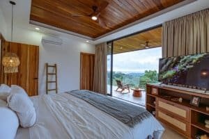 Modern bedroom with ocean view, wooden ceiling, and balcony in Dominical.