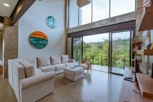 Spacious living room with large windows overlooking lush greenery and ocean.