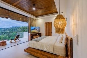 Modern bedroom with ocean view, wooden ceiling, and cozy decor in Dominical.