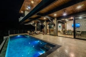 Modern house with pool, outdoor seating, and ocean view at night.