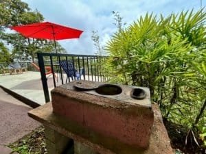 Outdoor deck with ocean view, red umbrella, and lush greenery in Dominical.