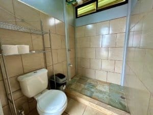 Bathroom with shower, beige tiles, and natural light in Dominical.