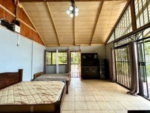 Interior of a Costa Rican cabin with two beds, large windows, and wooden ceiling.