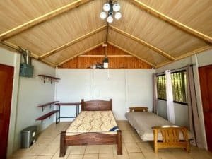 Interior of a cabin bedroom with two beds, wooden ceiling, and window view.