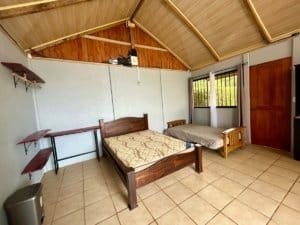 Bedroom with two beds and wooden ceiling in Dominical real estate property.