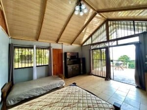 Interior of a cabin with ocean and valley view, large windows, and wooden ceiling.