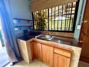 Small kitchen with wooden cabinets and mountain view through window.