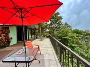 Balcony with red umbrella overlooking lush green landscape in Costa Rica.