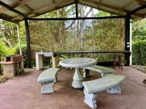 Covered outdoor patio with stone table, benches, and lush greenery in Dominical.