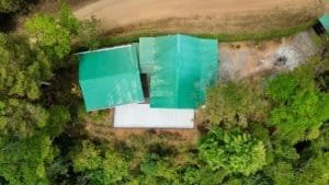 Aerial view of a cabin with green roofs surrounded by lush trees in Dominical, Costa Rica.