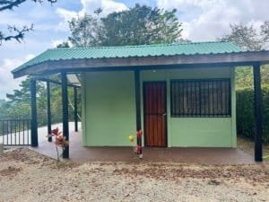 Small green cabin with wooden door and metal roof in Costa Rica.
