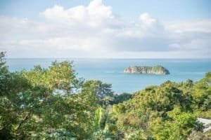 Scenic ocean view with lush greenery and island in the distance.