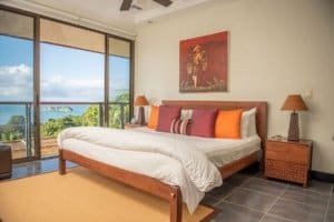 Elegant bedroom with ocean view, Balinese-inspired decor, and modern furnishings.