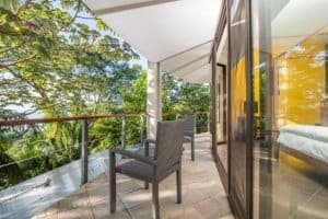 Balinese-style home balcony with ocean view and lush greenery.