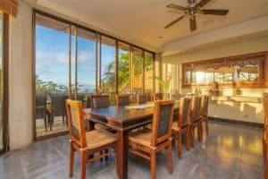 Elegant dining room with ocean view, tropical decor, and large windows.