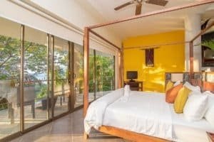 Spacious bedroom with ocean view, balcony, and tropical decor in Dominical.