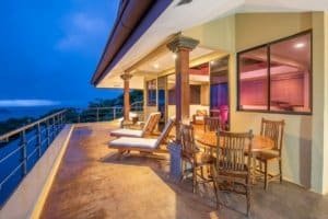 Balinese-style home balcony with ocean view and outdoor dining area.