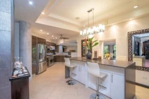 Modern kitchen with island, stainless steel appliances, and tropical decor.