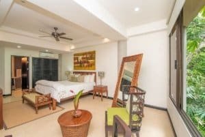 Spacious bedroom with ocean view, tropical greenery, and elegant decor.