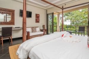Spacious bedroom with ocean view, balcony, and tropical surroundings in Dominical.