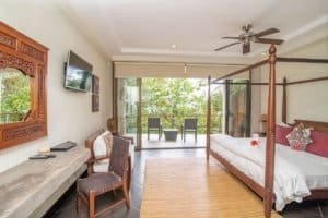Spacious bedroom with ocean view, balcony, and tropical surroundings.