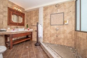 Elegant bathroom with walk-in shower, wooden accents, and natural stone tiles.