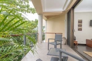 Balinese-style home balcony with ocean view and lush greenery.