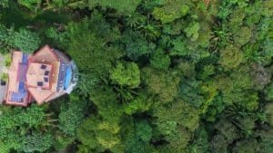 Aerial view of a lush tropical forest with a Balinese-inspired home and pool.