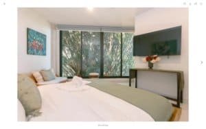 Modern bedroom with ocean view, large window, and tropical decor in Dominical.