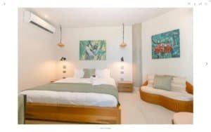 Spacious bedroom with ocean view, modern decor, and tropical artwork.