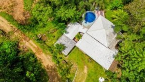 A fully renovated Costa Rican-style home surrounded by lush greenery and streams.