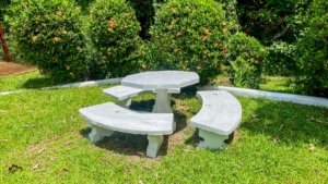 Stone table with curved benches in lush green garden setting.