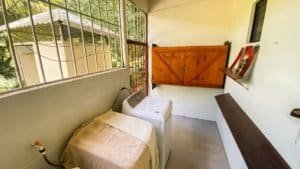 Laundry area with washing machine and wooden gate in Costa Rican-style home.