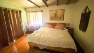 Comfortable bedroom with large bed, wooden furniture, and natural light from windows.