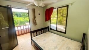 Bedroom with large windows overlooking lush greenery and streams.