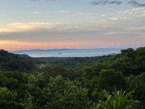 Scenic ocean view with lush rainforest and sunset sky in Dominical, Costa Rica.