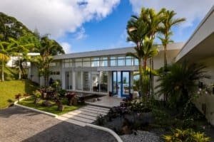 Modern estate with lush tropical landscaping and ocean in background.